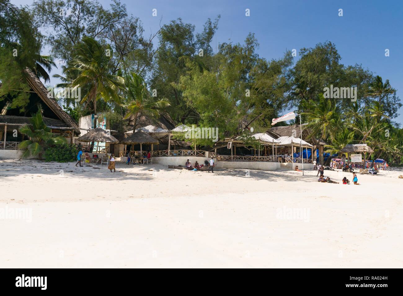 View of the exterior of Forty Thieves beach bar and restaurant with people outside on the beach on a sunny blue sky day, Diani, Kenya Stock Photo