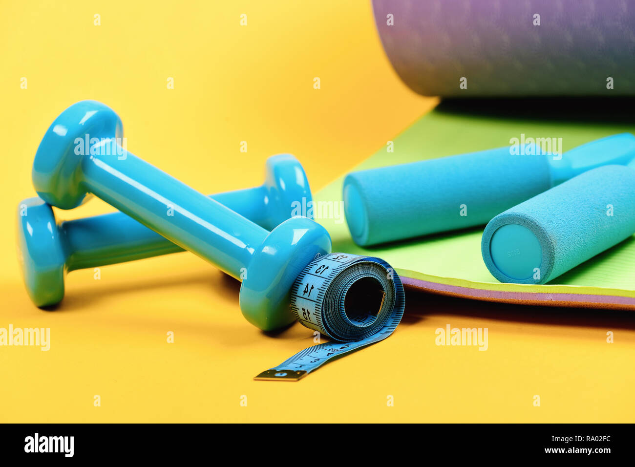 Shaping and fitness. Dumbbells, cyan jump rope and measure tape on