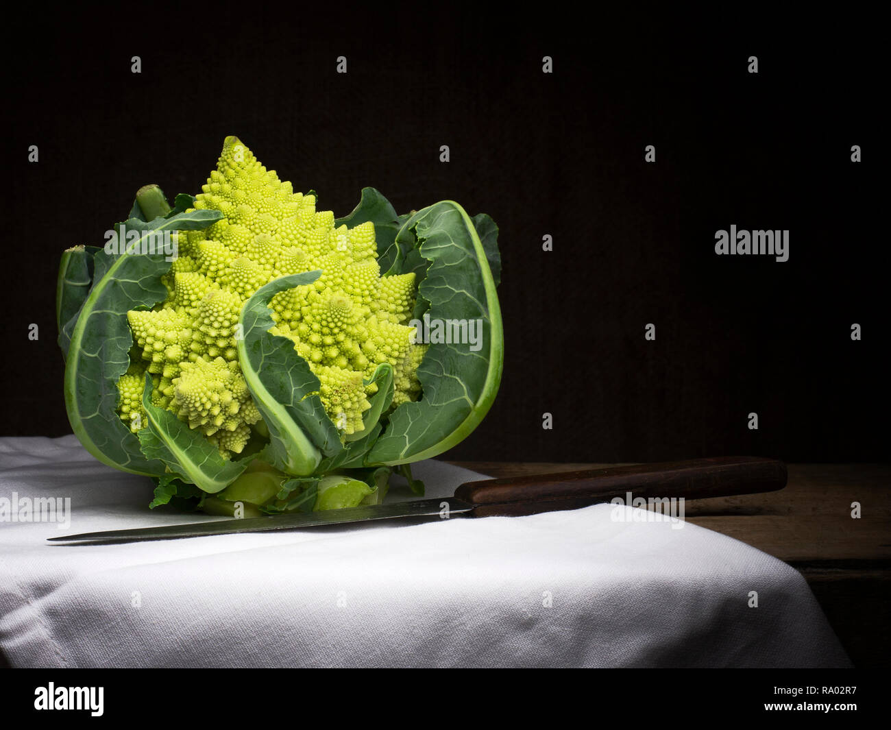 Romanesque aka romanesco broccoli with white cloth and knife. Still life, food. Broccoflower. Stock Photo