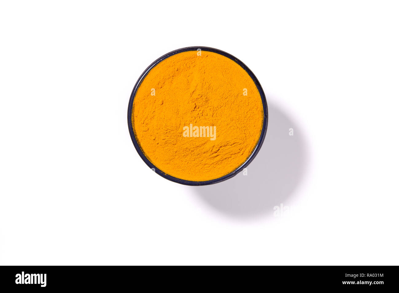 Curcuma turmeric spice powder in round bowl isolated with shadow on white background, view directly from above. Stock Photo