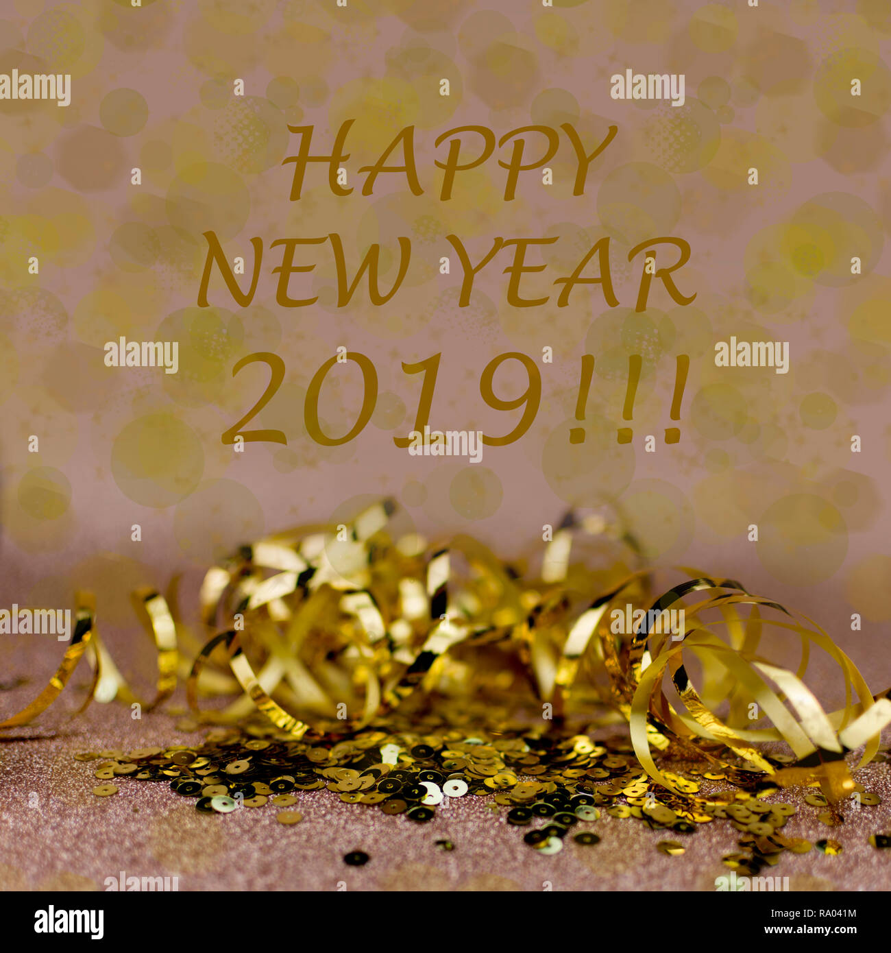 New Year 2019 greetings card. Golden ribboon and sequins on warn soft pink background. Stock Photo