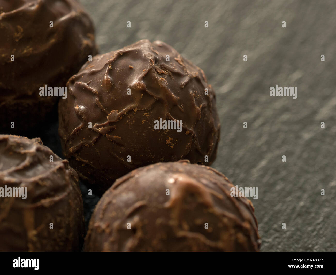 Close-up of round chocolate pralines on a slate plate Stock Photo