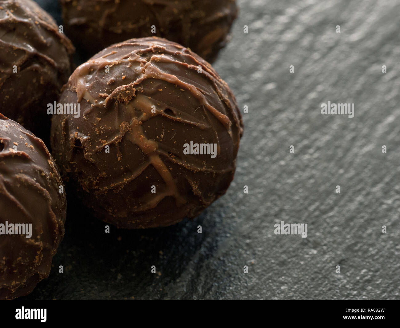 Close-up of round chocolate pralines on a slate plate Stock Photo