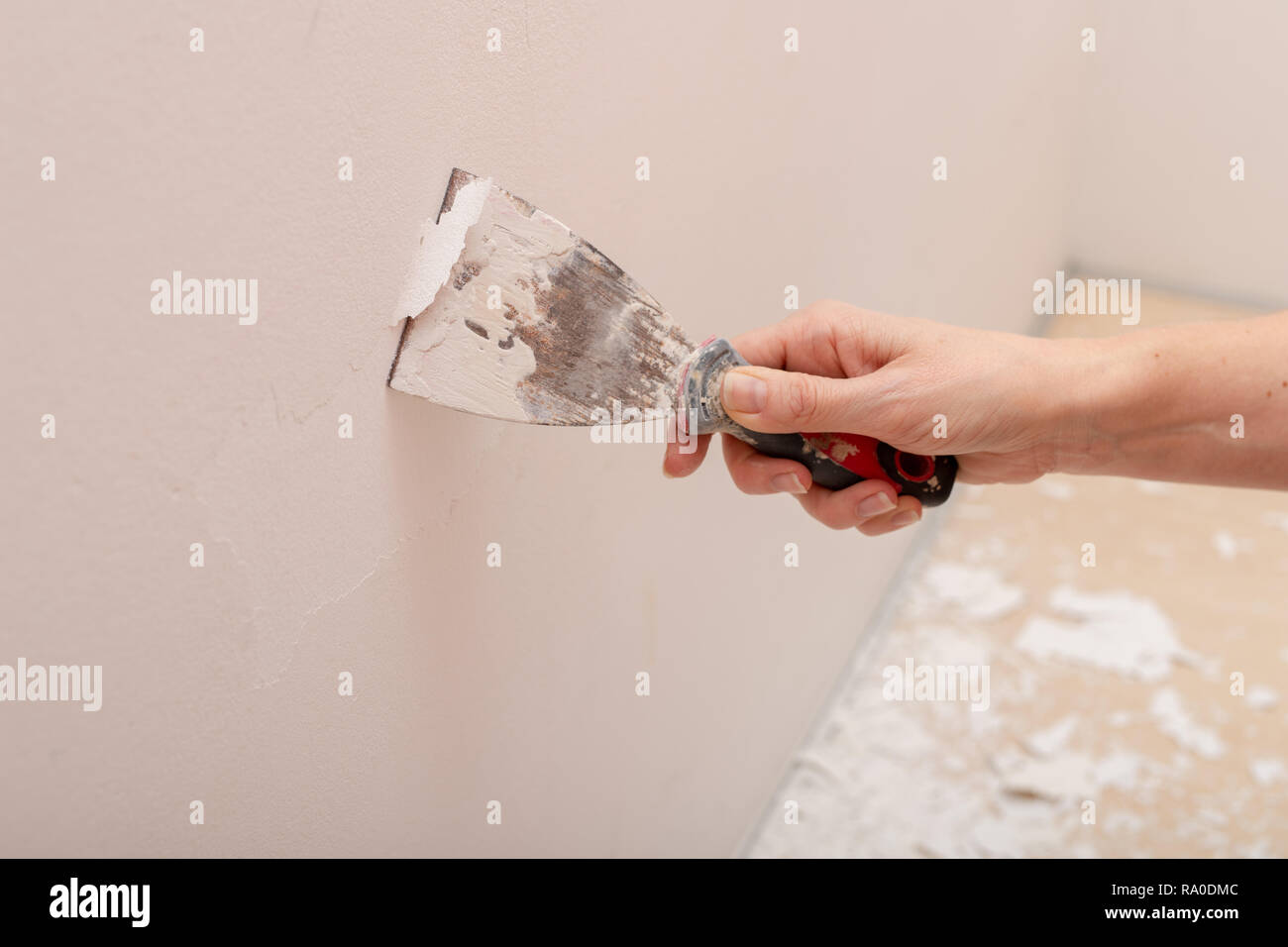 Stripping old paint from the wall. Renovation and painting of walls in the apartment. Place - home farm. Stock Photo