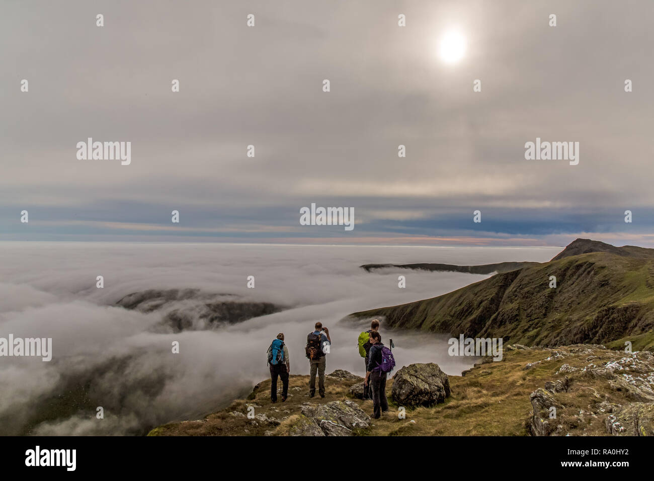 A group of hikers in the Aran Mountains in the Southern Snowdonia Range in North Wales, looking over a temperature inversion. Stock Photo