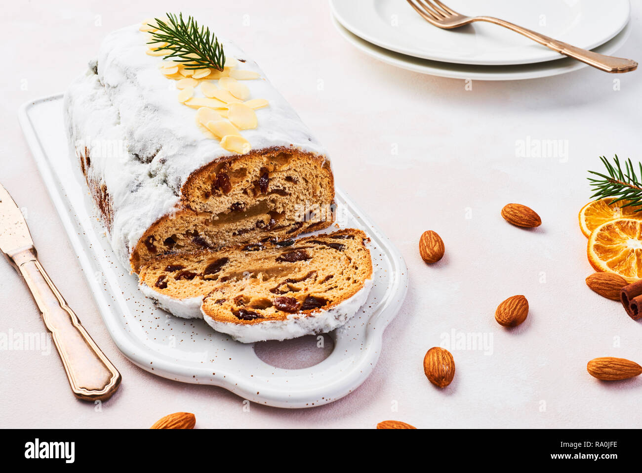 Christmas Stollen cake with icing sugar, marzipan, almonds and raisins on white serving plate. Traditional Dresdner christ pastry. Stock Photo