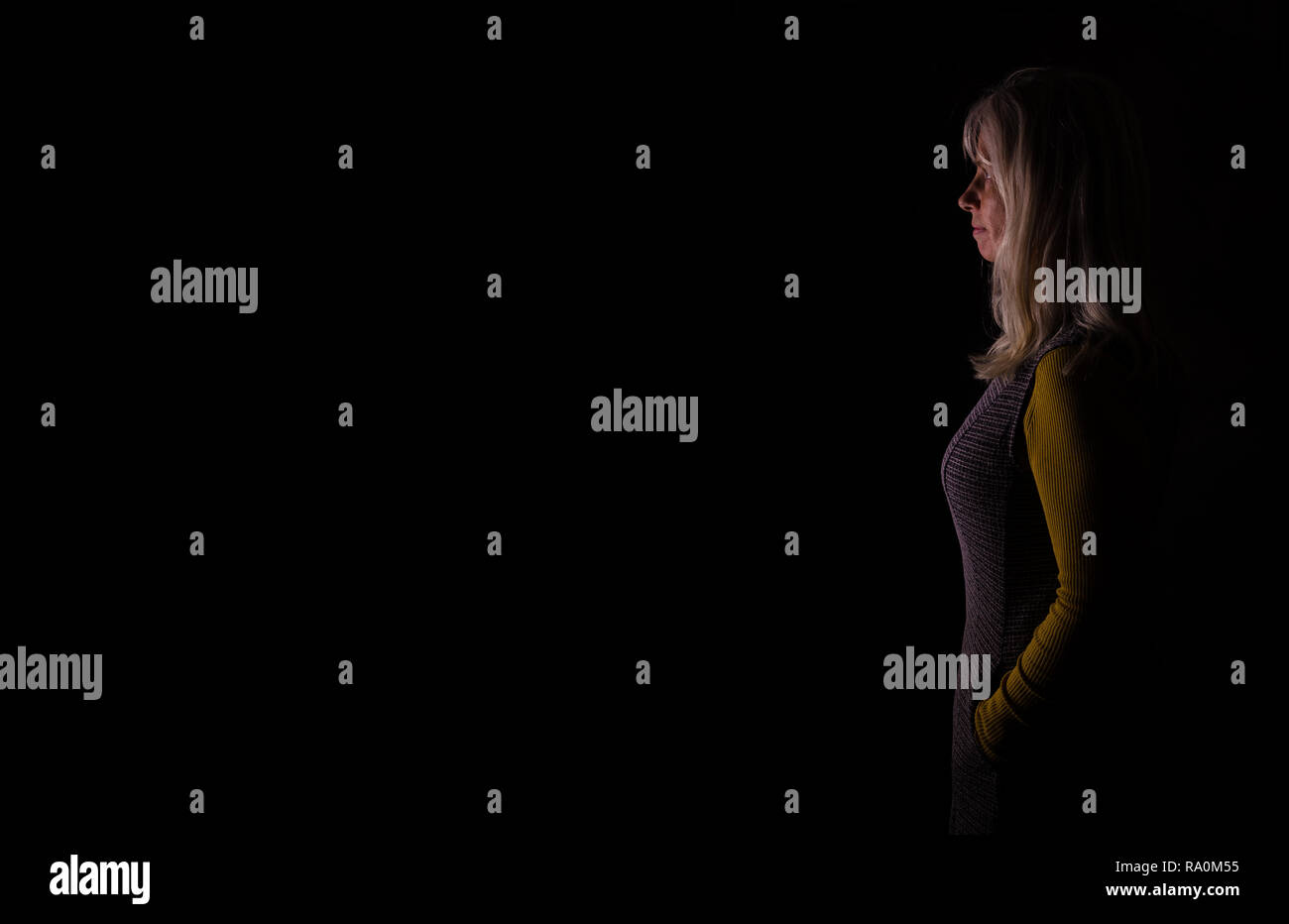 Middle aged woman in profile staring into black negative space Stock Photo