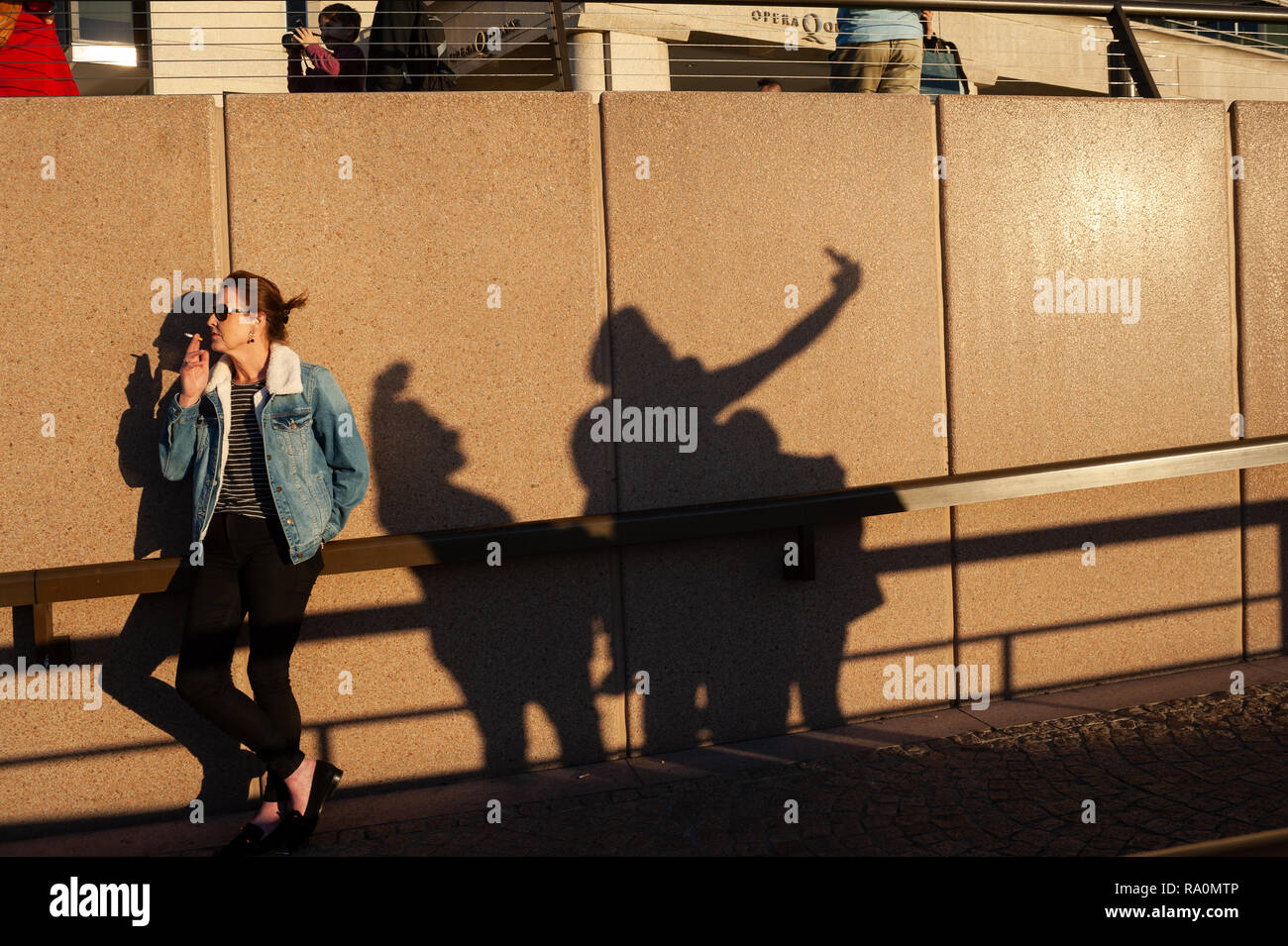 16.09.2018, Sydney, New South Wales, Australien - Eine Frau geniesst die Abendsonne waehrend sie am Circular Quay eine Zigarette raucht und neben ihr  Stock Photo