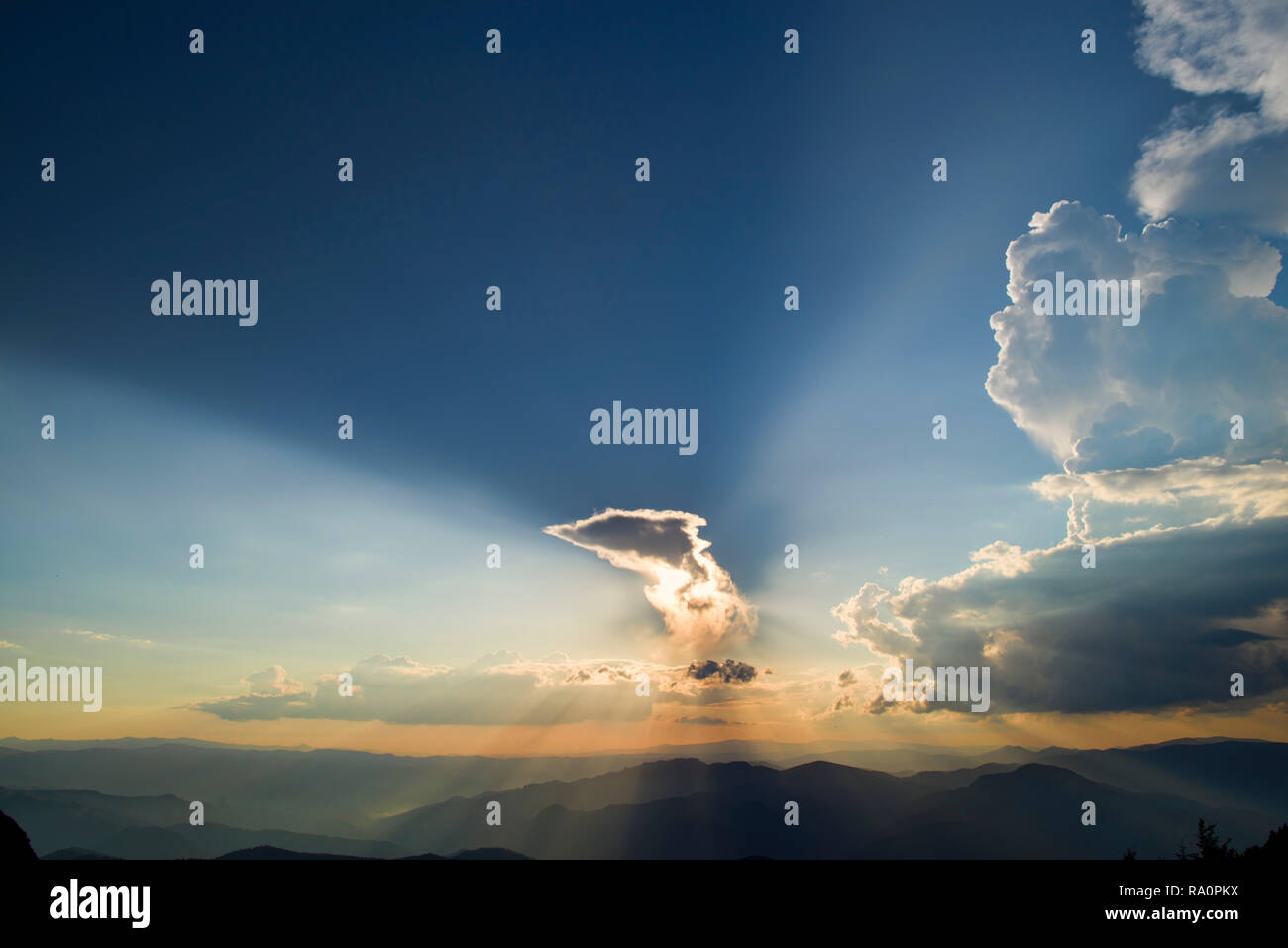 Sunset over clouds from the top, Sun rays over the mountains Stock Photo