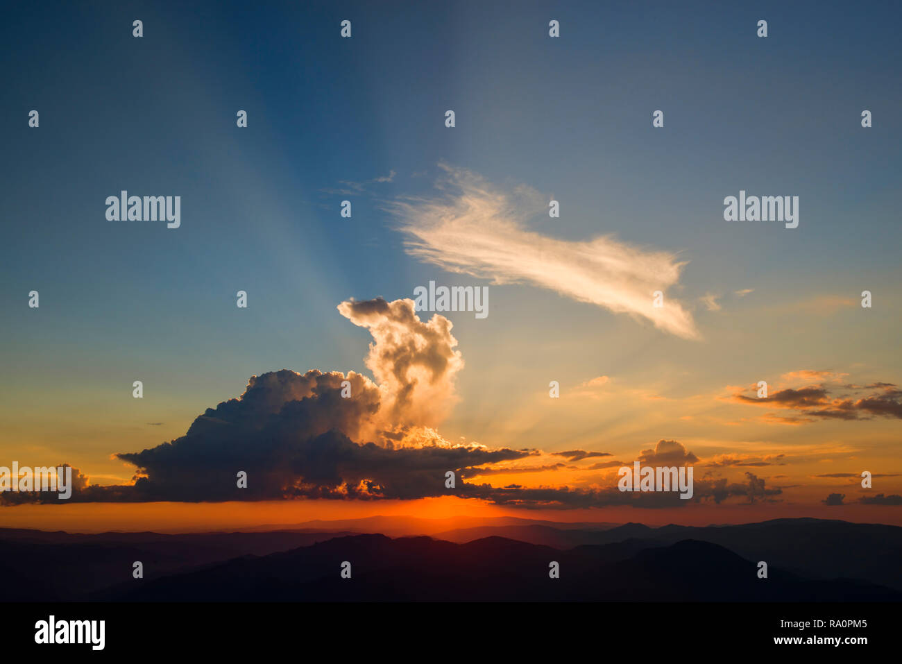 Orange sunset, sun rays breaking the clouds Stock Photo