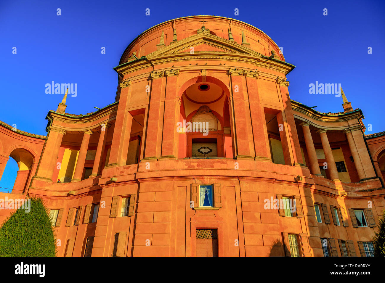 Facade of San Luca Holy Mary Sanctuary of Bologna at sunset light. The Catholic cathedral of San Luca is located on the hills of Bologna city. Sunny with blue sky. Stock Photo