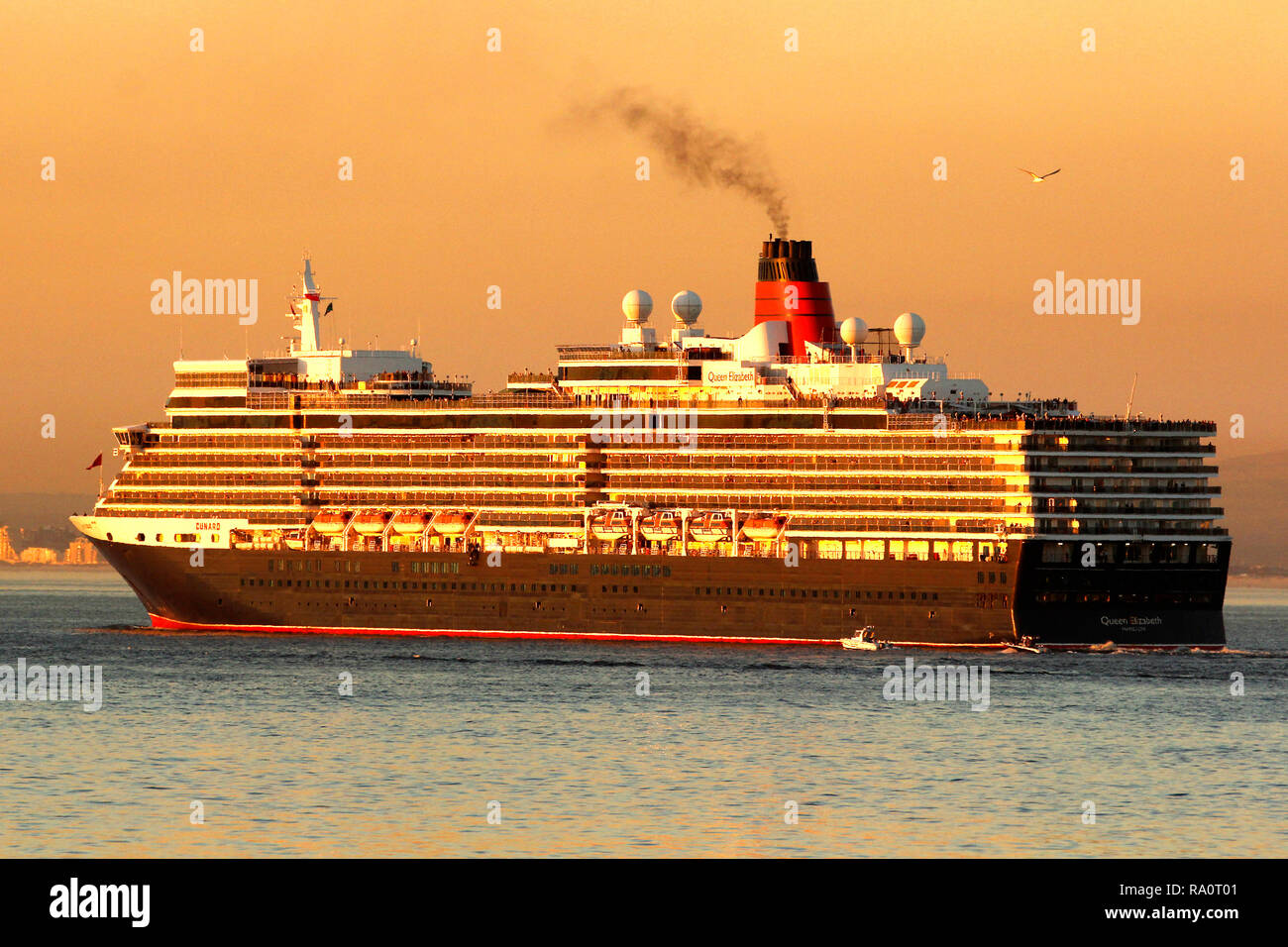 The Queen Mary 2 sailing out of Cape Town Harbour at sunset. Western Cape Province, South Africa. Stock Photo