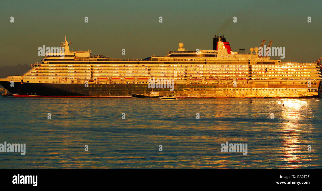The golden Queen Mary 2 sailing out of Cape Town Harbour at sunset