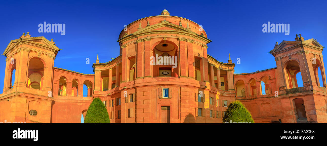 Wide angle panorama San Luca Holy Mary Sanctuary of Bologna at sunset. The Catholic cathedral of San Luca is located on the hills of Bologna city. Sunny with blue sky. Banner cityscape. Stock Photo