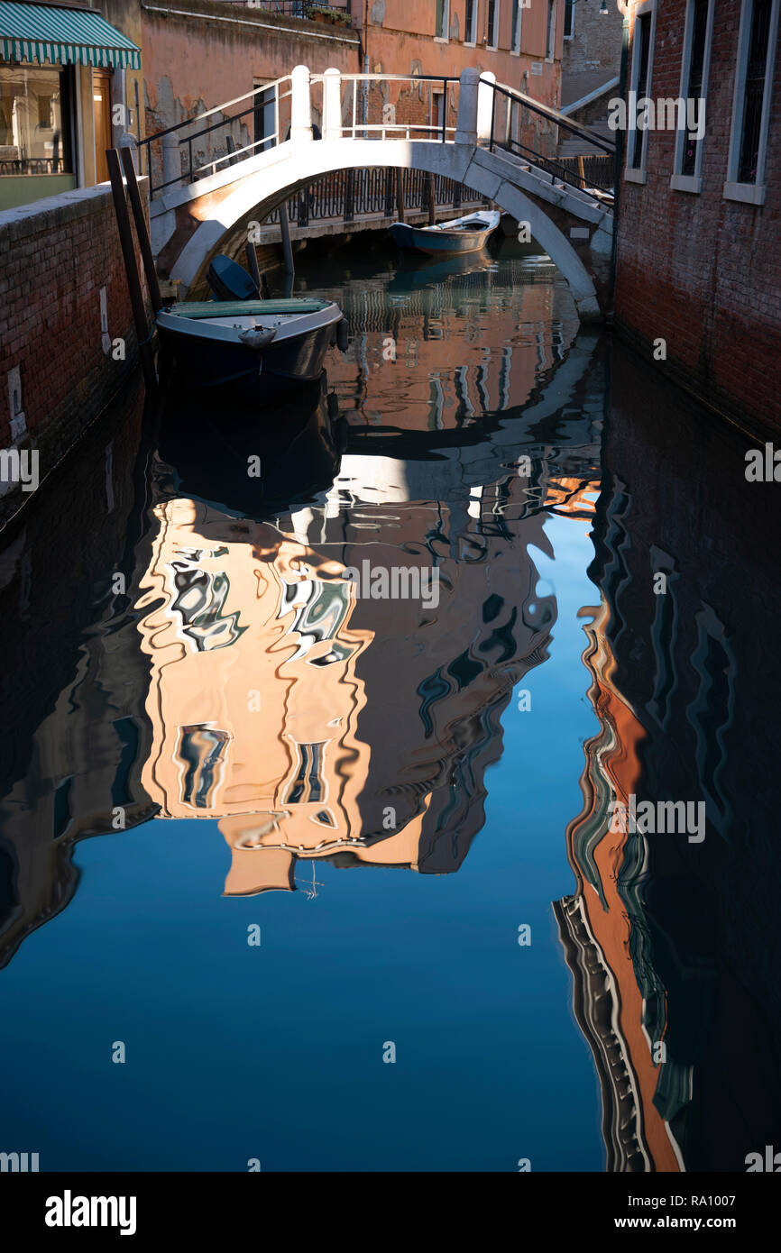 Side canal with bridge and reflections, Venice, Italy. Stock Photo