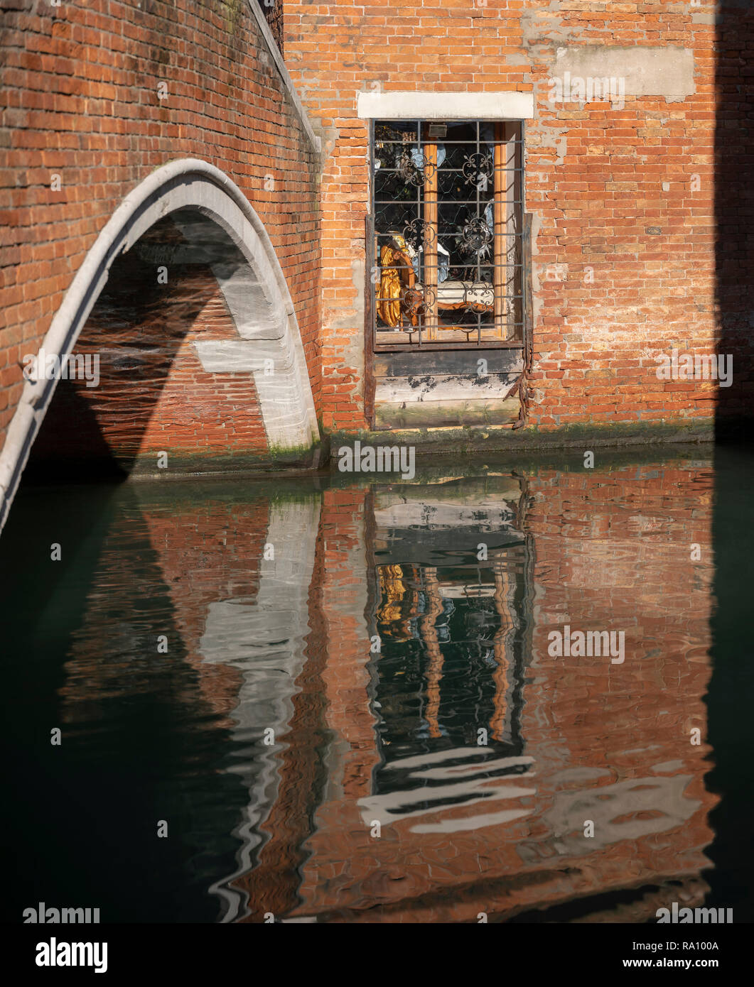 Side canal with bridge and reflections, Venice, Italy. Stock Photo