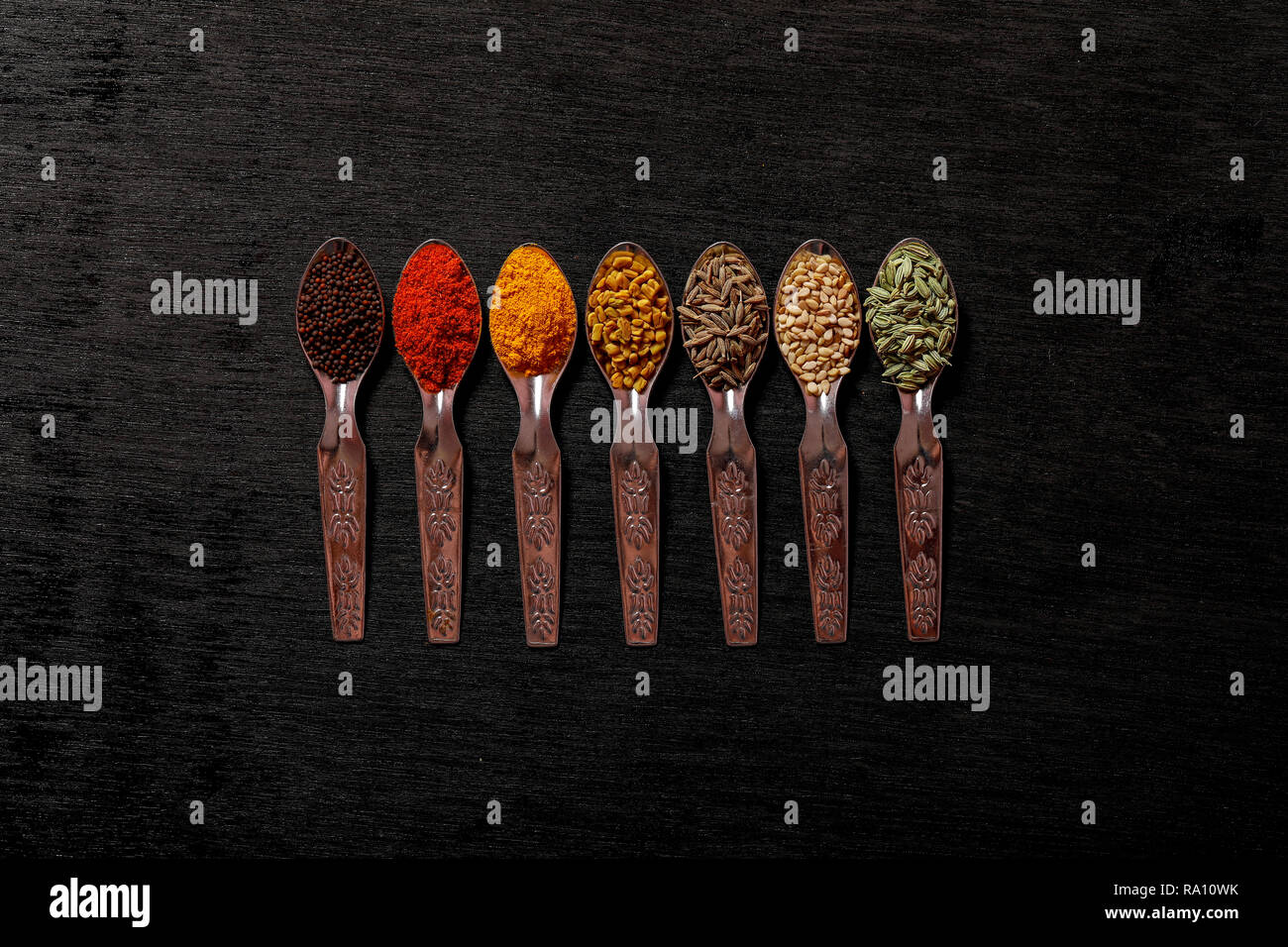 spices in spoons on black background Stock Photo - Alamy