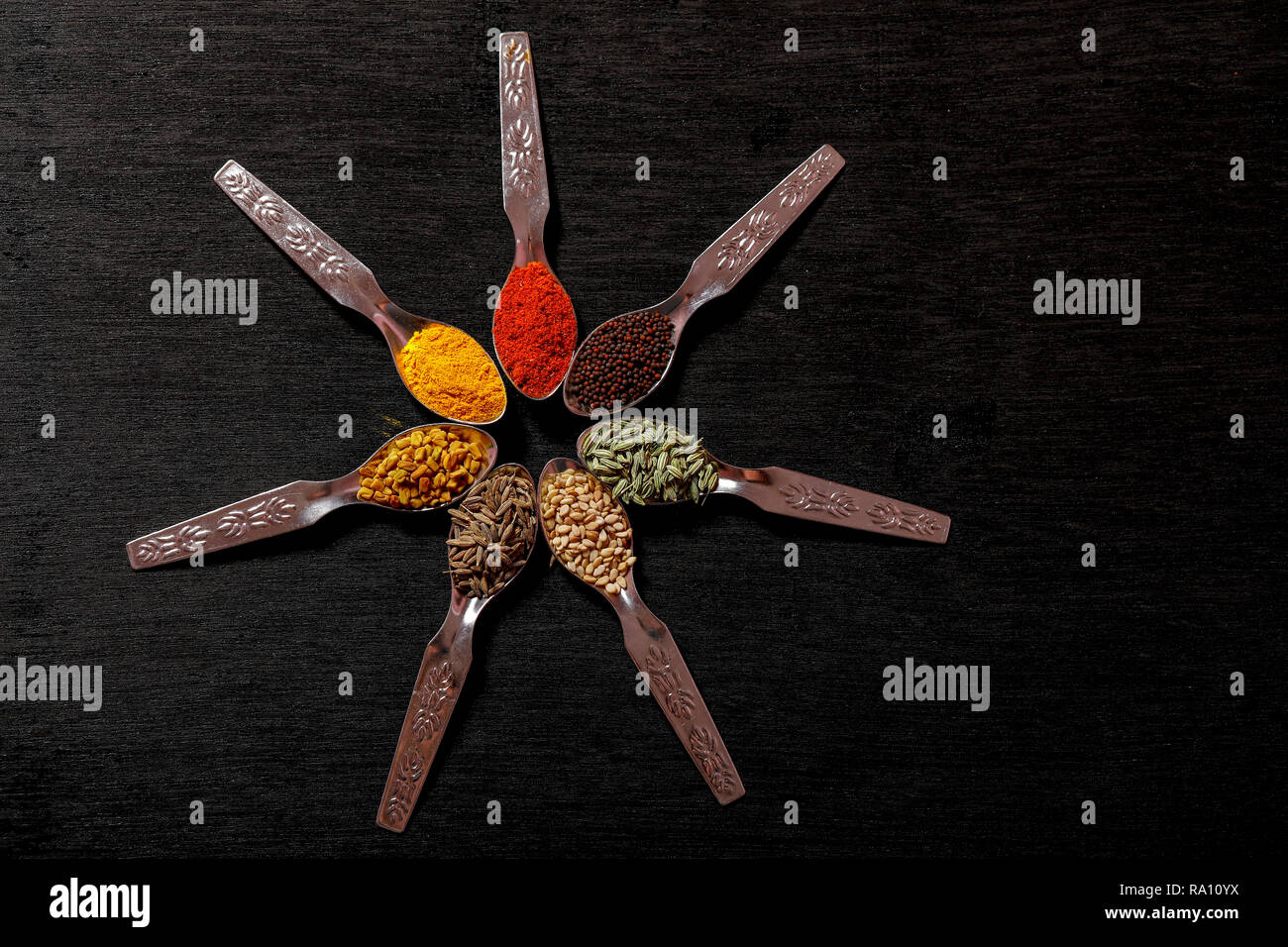 spices in spoons on black background Stock Photo