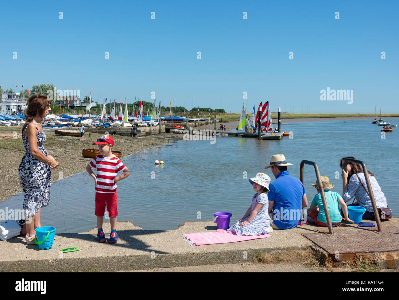 Family fishing off jetty on Orford Quay, Orford, Suffolk, England