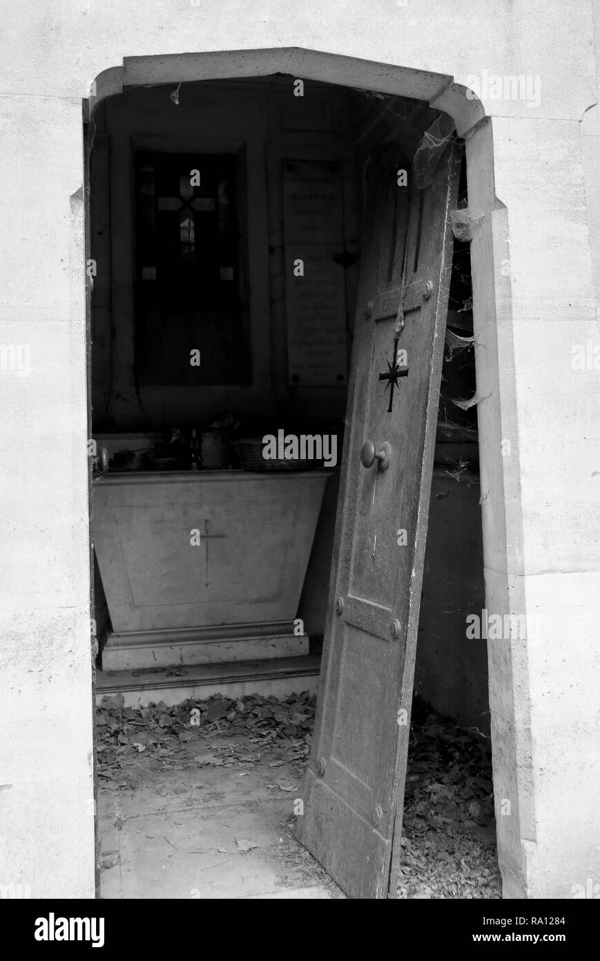 broke door of an old grave in the abandoned cemetery with black and white toned effect Stock Photo
