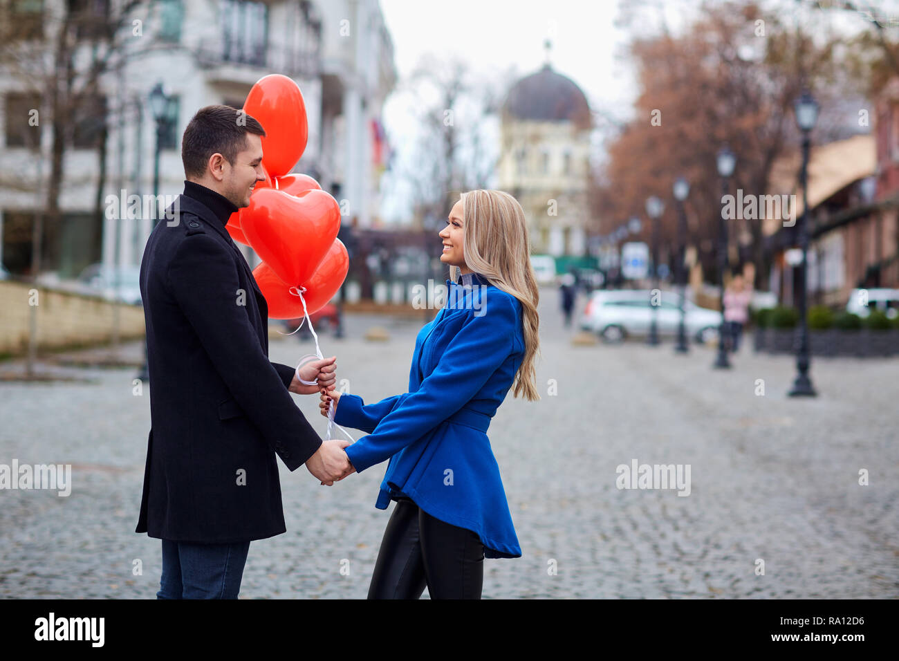 A loving couple in a coat with balloons hearts in hands Stock Photo - Alamy