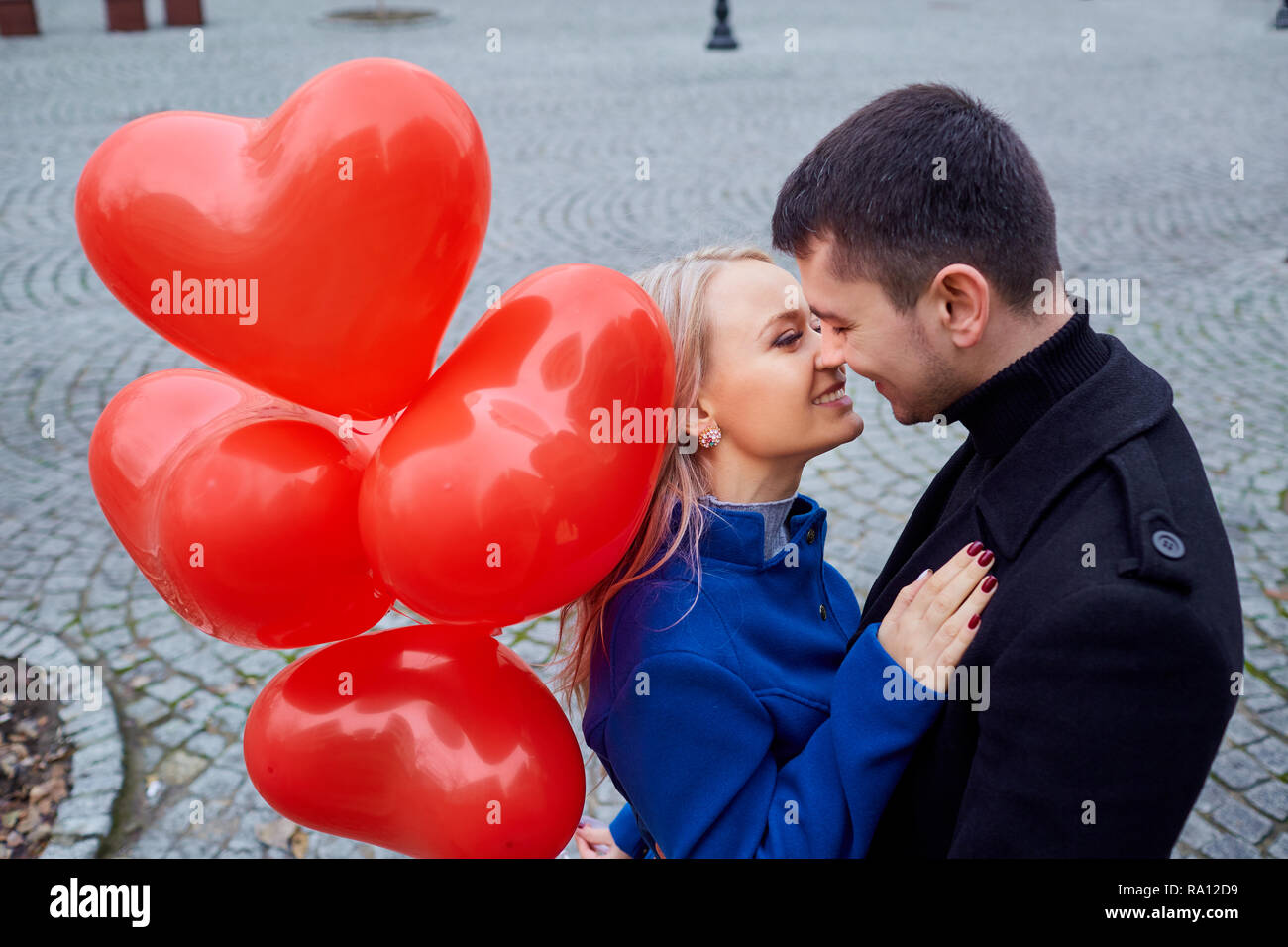 A loving couple in a coat with balloons hearts in hands Stock Photo - Alamy