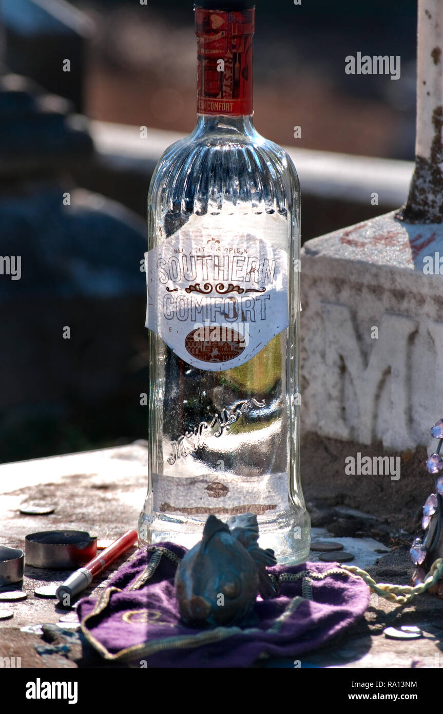 A liquor bottle, with candles and a fish figurine, sits on the grave of gypsy queen Kelly