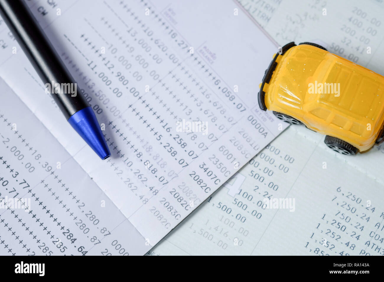 Yellow toy car and pen put on a bank passbook on top-view, with concept to pay in installments. In order to buy car Stock Photo