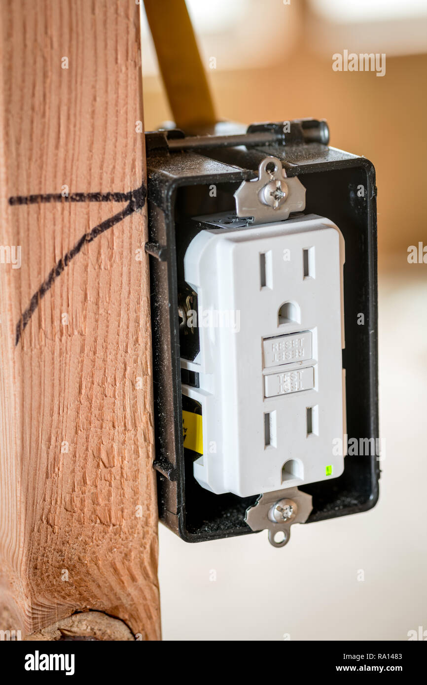 Close up of a white plastic electrical outlet with the faceplate removed mounted to a stud Stock