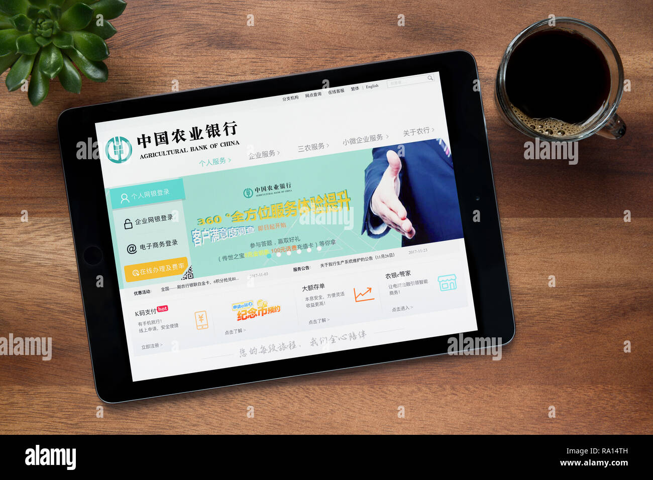 The website of Agricultural Bank of China is seen on an iPad tablet, on a wooden table along with an espresso coffee and house plant (Editorial only). Stock Photo