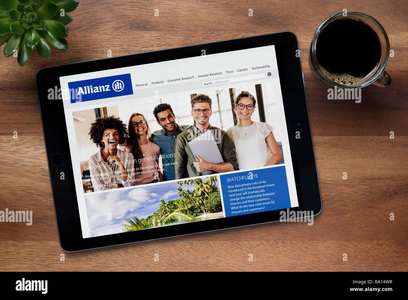 The website of Allianz insurance is seen on an iPad tablet, on a wooden table along with an espresso coffee and a house plant (Editorial use only). Stock Photo