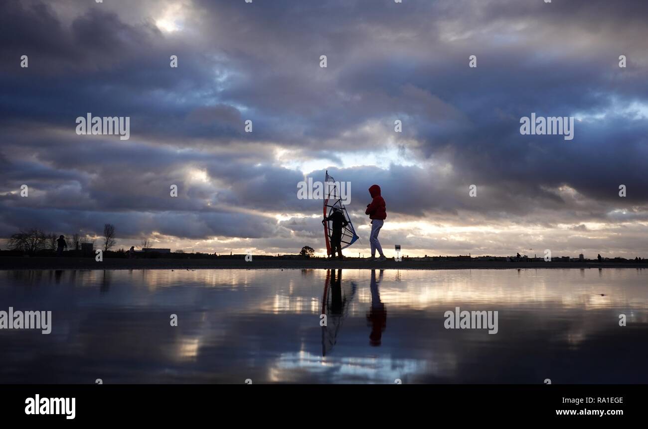 Berlin, Germany. 30th Dec, 2018. The sky is reflected in a puddle of rain in front of a wind skater and a walker on the Tempelhof field. Credit: Kay Nietfeld/dpa/Alamy Live News Stock Photo
