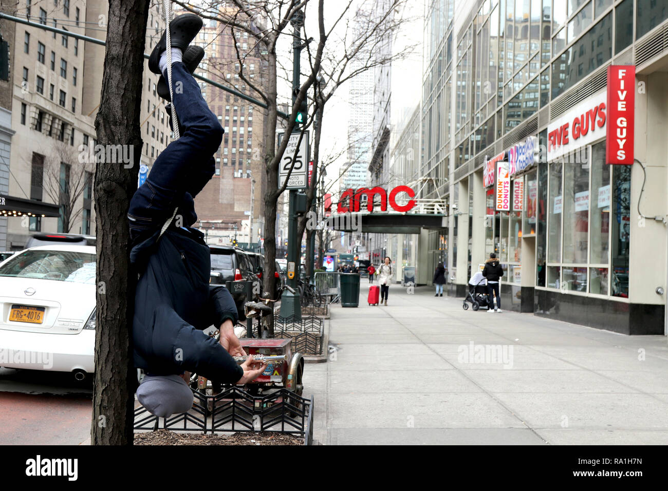 New York, USA. 30th Dec, 2018. At first, you hear him, then you see Jose Cohen of Huntington, Long Island, New York just hanging around, upside down from a tree, playing his flute drawing stares, comments and donations on busy 34th. Street in Manhattan on 30 December 2018. Credit: G. Ronald Lopez/ZUMA Wire/Alamy Live News Stock Photo