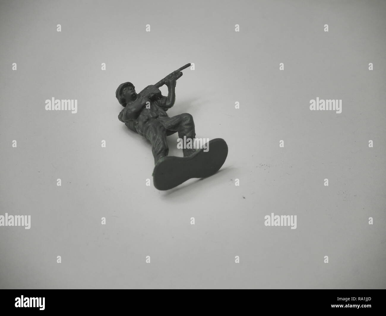 Black and White Image of Green Army Man Laying on Wooden Table Stock Photo