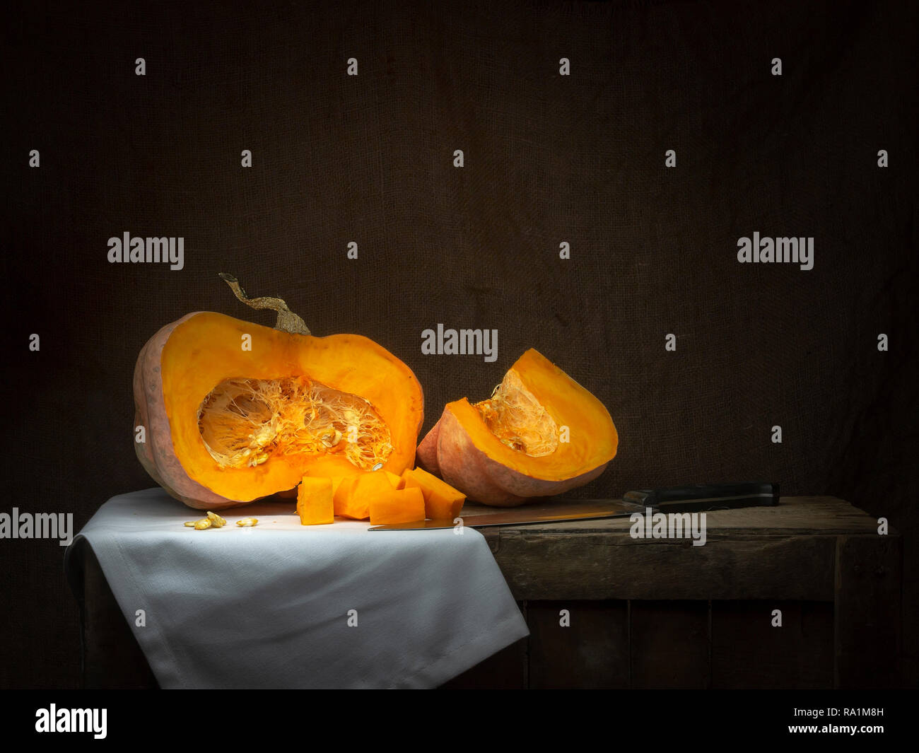 Acorn winter squash, pumpkin, prepared for cooking, cubes with seeds. LIfe and death metaphor. Chiaroscuro, baroque style light painting. Stock Photo