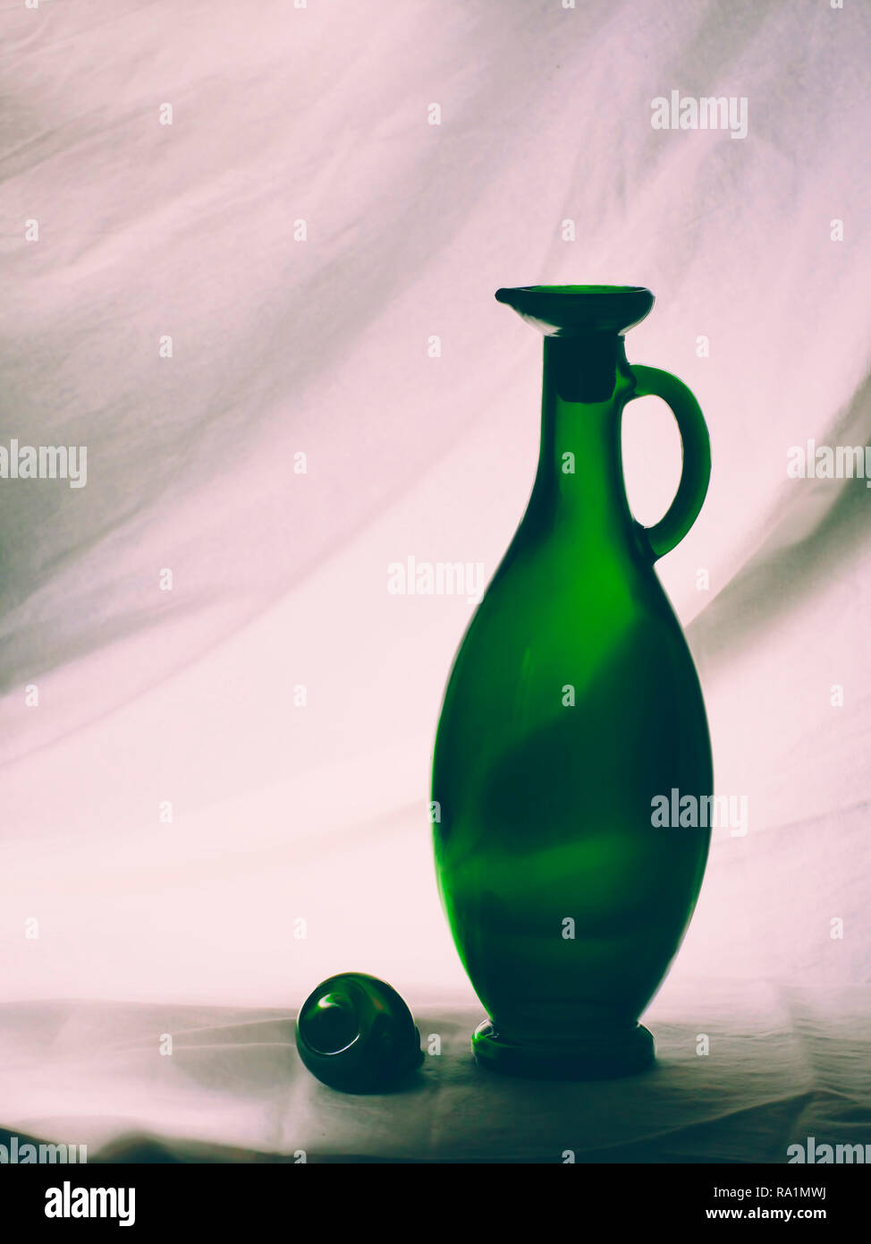 Vintage green glass olive oil bottle, backlit. Light painting. Stock Photo