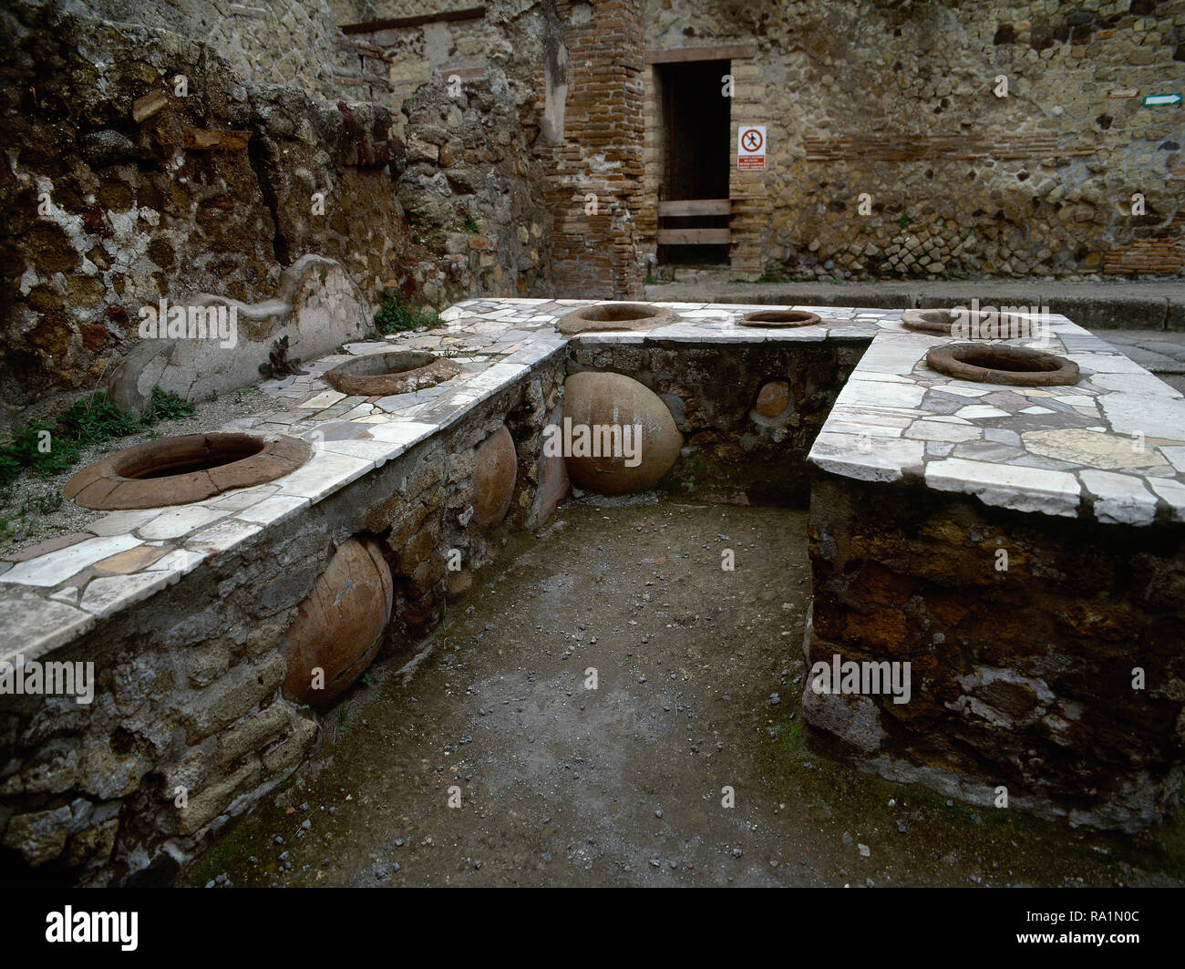 Italy. Herculaneum. Ancient Roman city destroyed by the eruption of the Vesuvius in 79 AD. Bar counter with holes, where jars were set into them (dolia) for food or wine. Campania. Stock Photo
