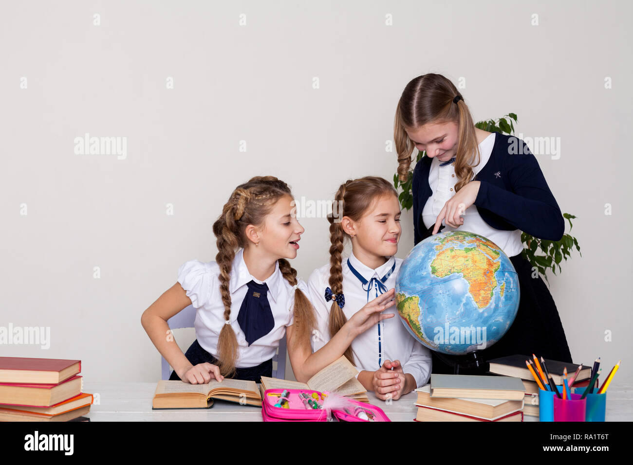 three girls schoolgirls on the lesson of geography with a globe in ...