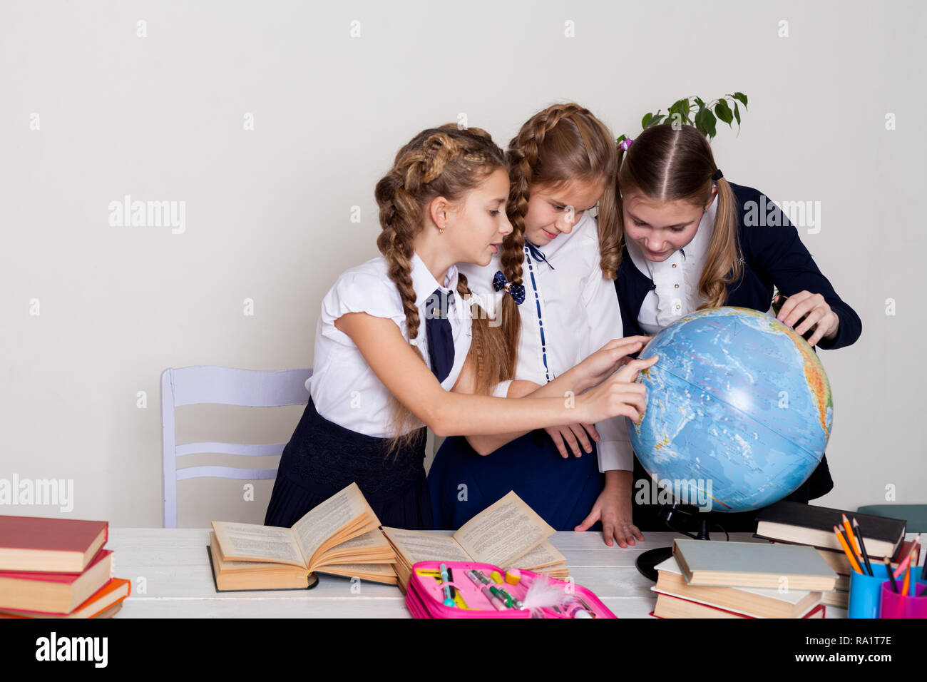 three girls schoolgirls on the lesson of geography with a globe in ...