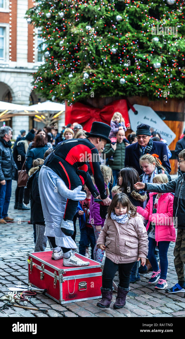 A street entertainer receiving money tips from kids after show, Covent Garden, London, England, UK. Stock Photo