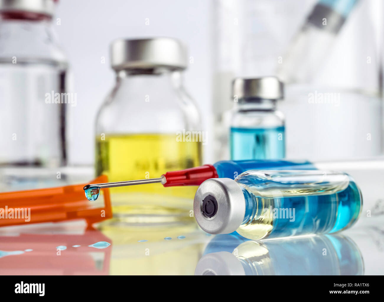 Syringe with medication drips next to vials in a hospital, conceptual ...