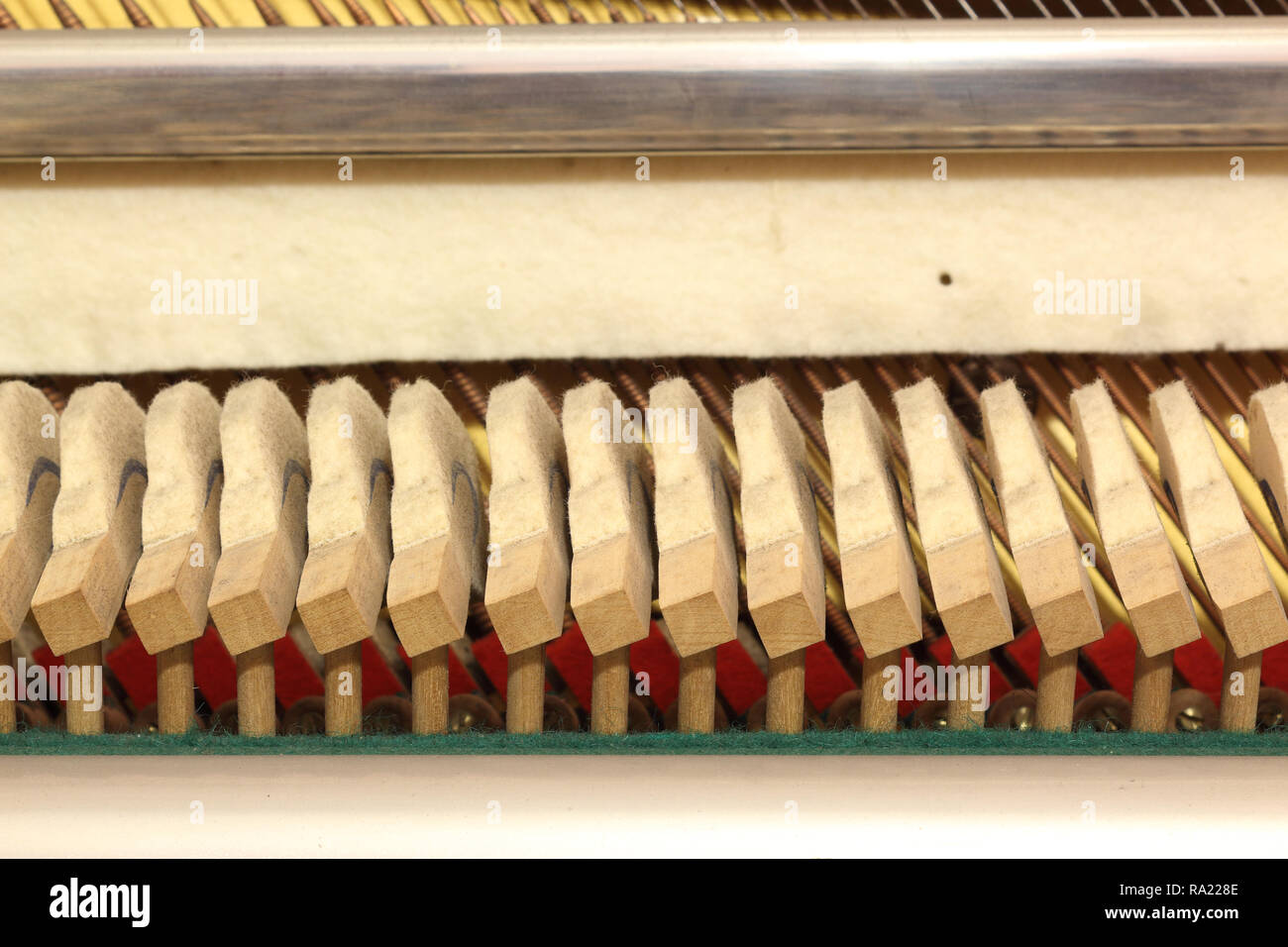 A close view of wooden hammers on their shanks, in a upright piano