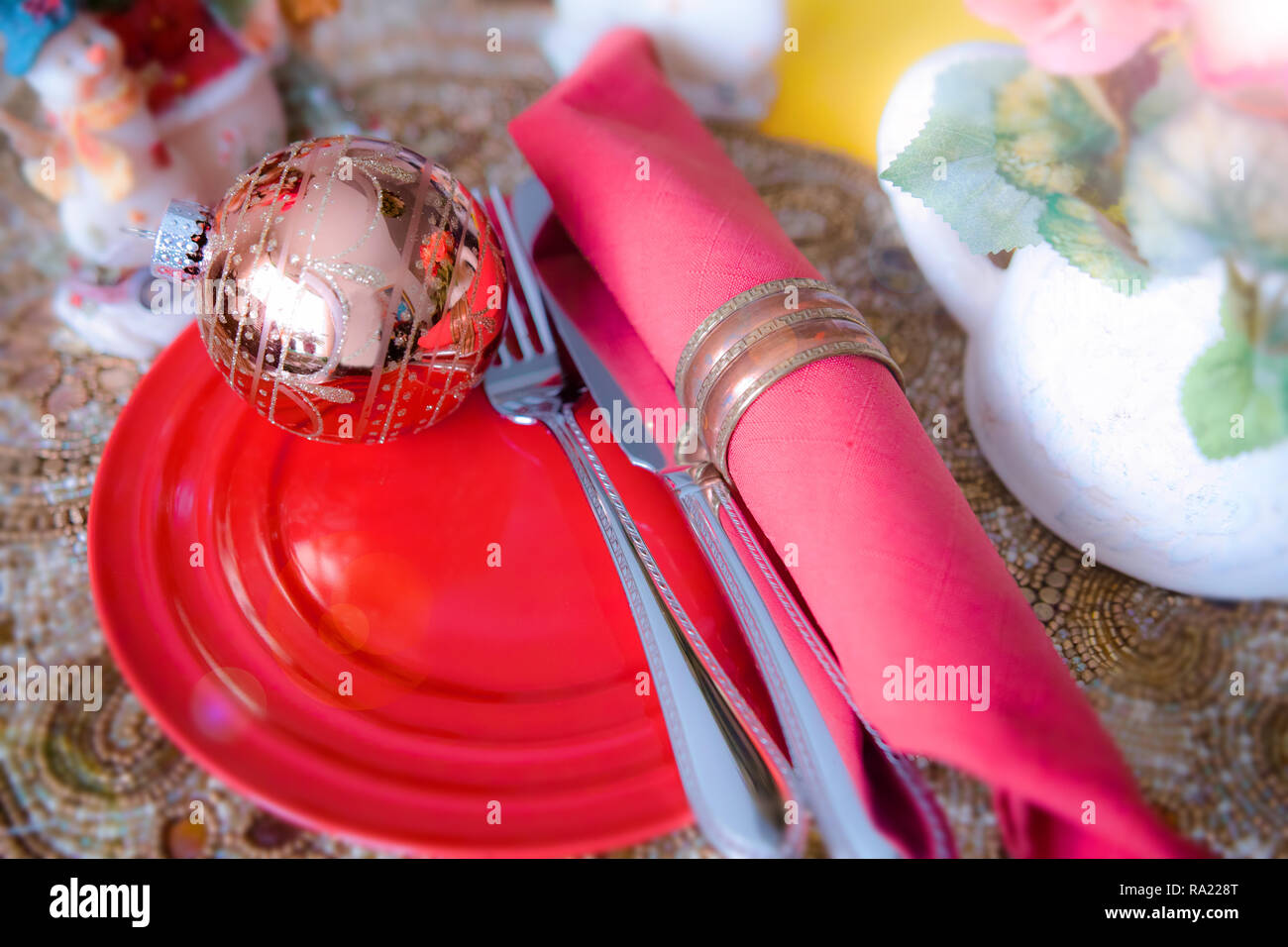 The table is set for the Christmas party. A golden ball is placed on the red dish. Stock Photo