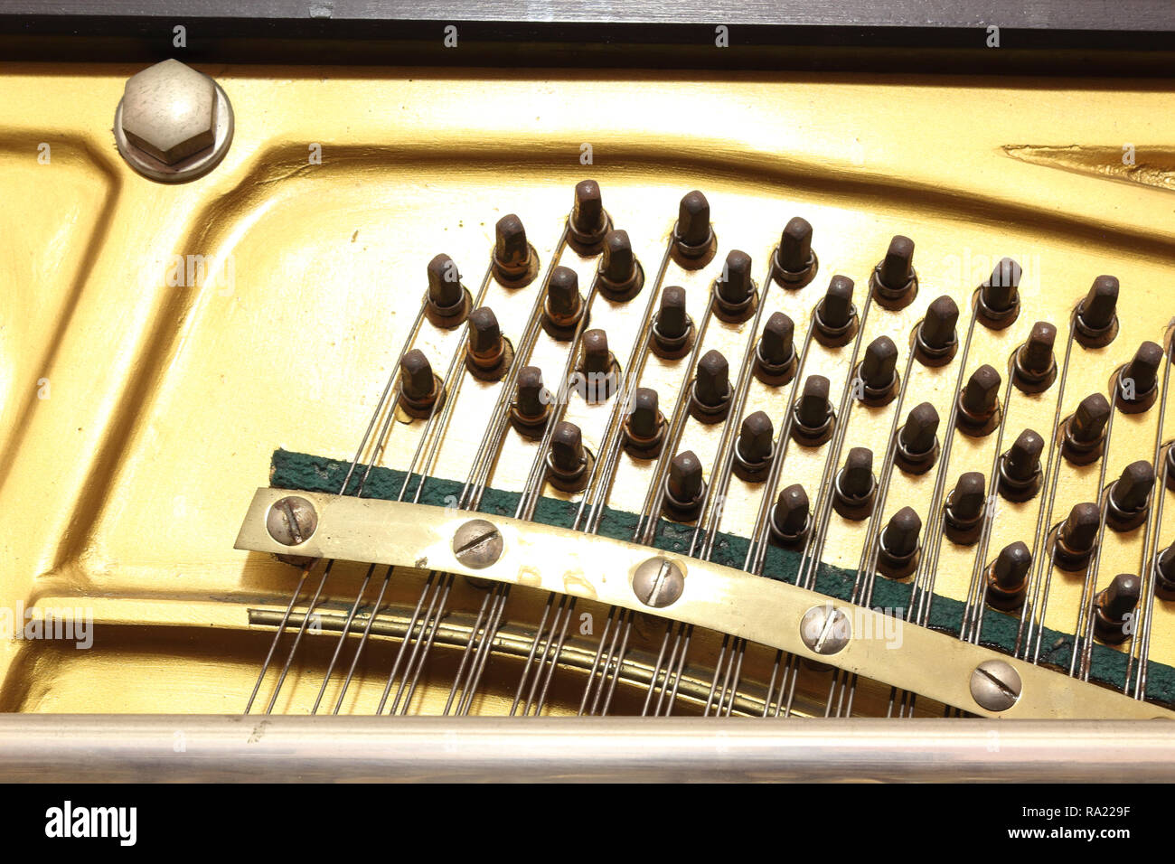 A close view of the plate of an upright piano musical instrument, with hitch  pins used for tuning the strings, which pass over the bridge Stock Photo -  Alamy