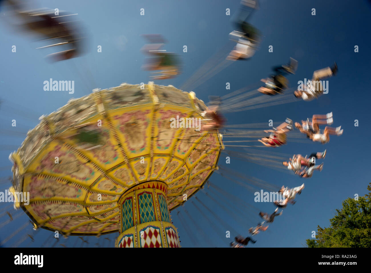 A spinning merry go round swing at the fair, people riding in motion