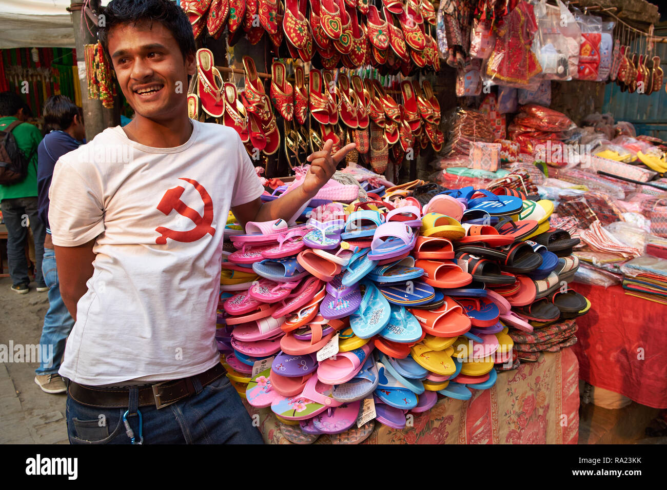 A footwear vendor in a market in Kathmandu, Nepal, selling cheap plastic  shoes, his shirt displaying the communist hammer and sickle symbol Stock  Photo - Alamy