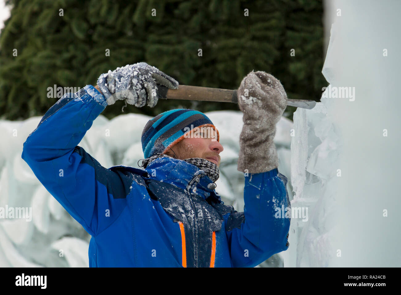 The sculptor cuts an ice figure for Christmas from a block of ice with ...