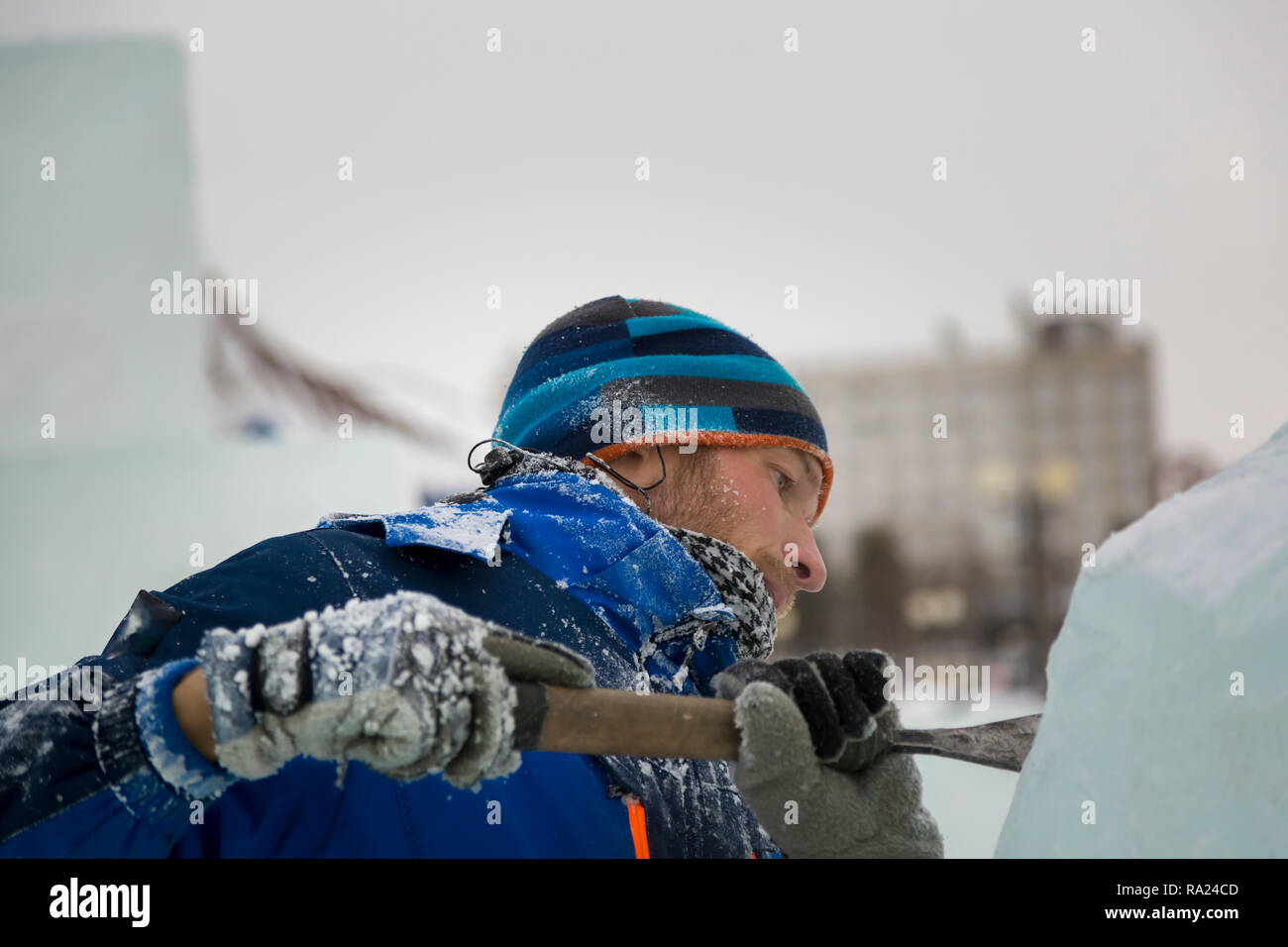 The sculptor cuts an ice figure for Christmas from a block of ice with ...