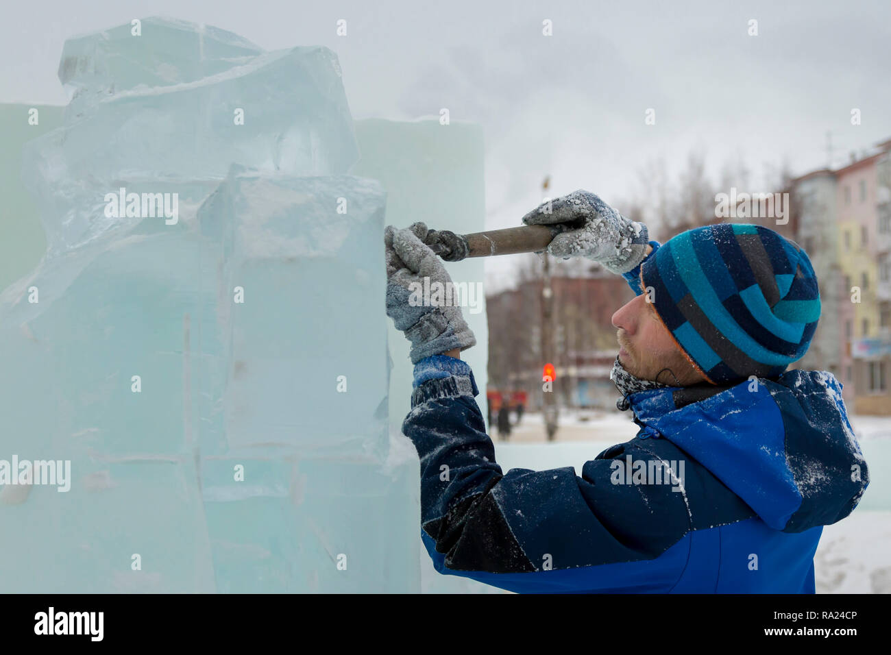 The sculptor cuts an ice figure for Christmas from a block of ice with ...