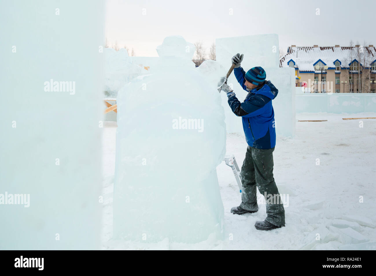 The sculptor cuts an ice figure for Christmas from a block of ice with ...